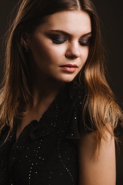 Fashion studio portrait of young beautiful woman on black background