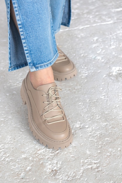 Fashion studio shot. Girl in denim jeans and casual sneakers on concrete background. Urban lifestyle concept photo