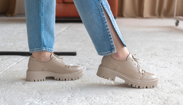 Fashion studio shot. Girl in denim jeans and casual sneakers on concrete background. Urban lifestyle concept photo