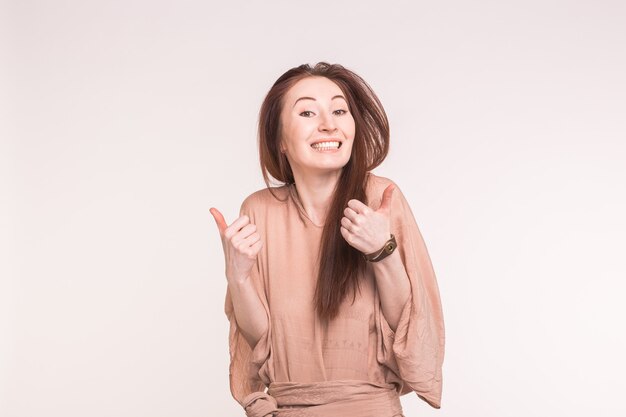 Fashion, style and gesture concept. happy smiling young woman over white showing thumbs up.