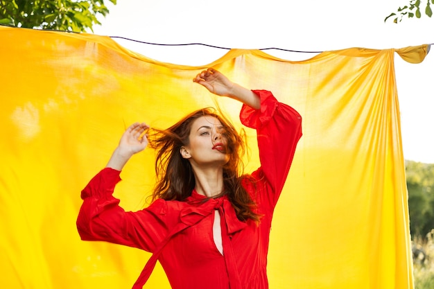 Fashion style girl in a red dress posing on a yellow background