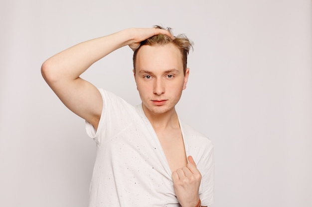 Fashion, style, people concept - Portrait of young tender redhead teenage man with healthy freckled skin wearing white top looking at camera with serious or pensive expression.