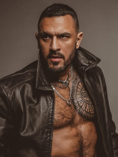 Fashion style portrait of handsome guy. Fashion brutal guy with sexy naked torso in leather jacket.