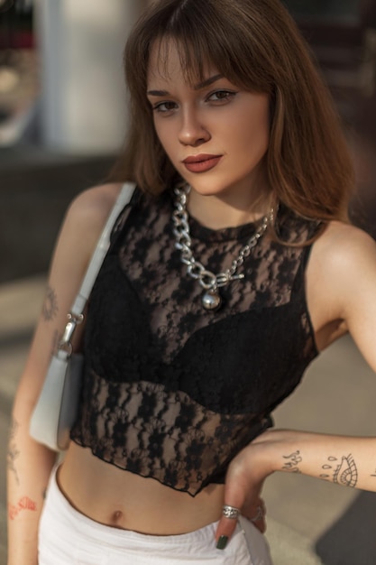 Модная летняя городская девушка в стильном сексуальном черном кружевном топе и юбке с сумкой ходит по улице