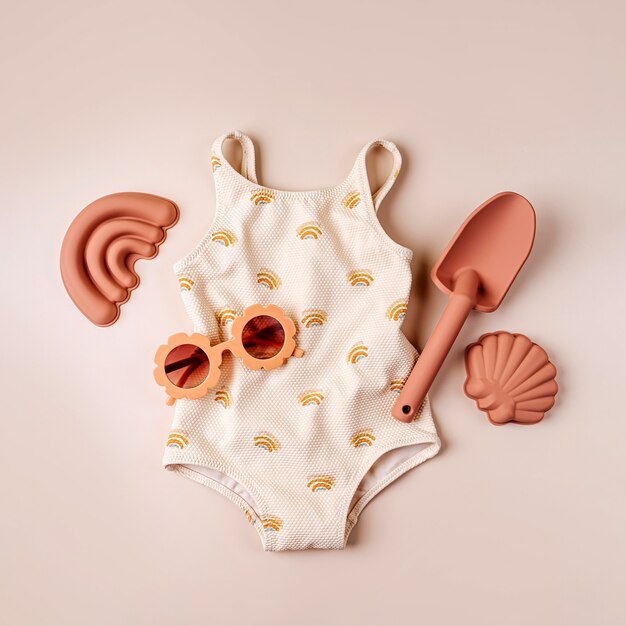 Fashion swimsuit and sunglasses with beach toys. Top view of beach summer accessories for children. Modern set for vacation. Flat lay