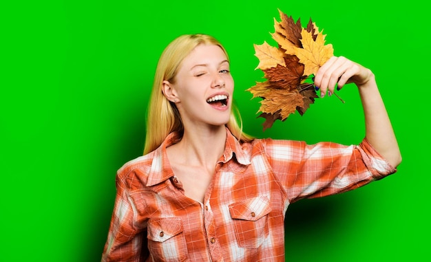 Fashion trend for fall beautiful winking girl in plaid shirt with autumn leaves blonde model with