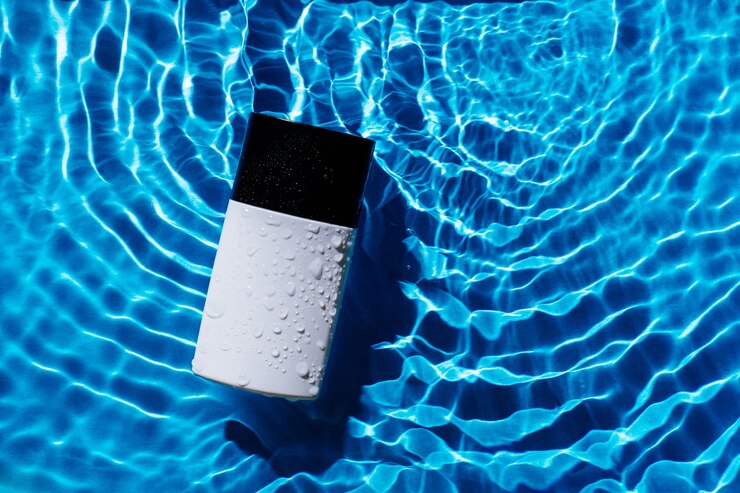 青い波の湿気のしぶきの背景に香水のトイレの水のファッション流行のボトル美容製品のコピースペース
