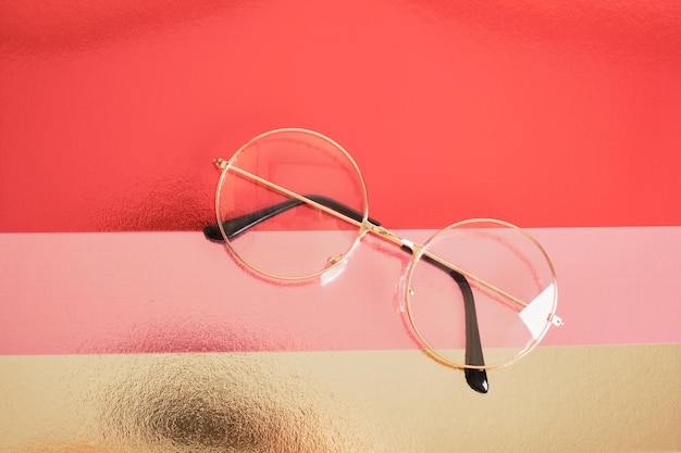 Photo fashion trendy eyes glasses for correcting vision on a creative background, colorful pink and golden shiny cardboard background, copy space