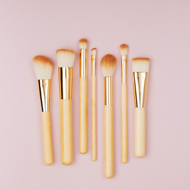 Fashion various makeup brushes on a pastel pink background