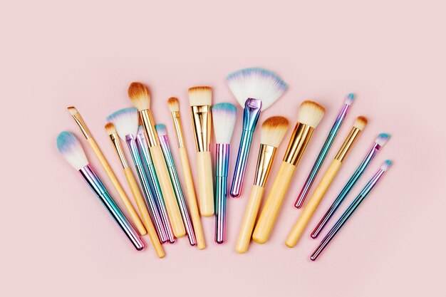 Fashion various makeup brushes on a pastel pink background