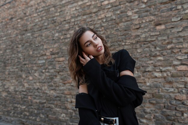 Fashion woman in black clothes walks on the street