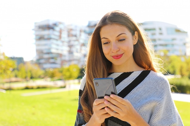 Fashion woman chatting with smart phone app in city park.