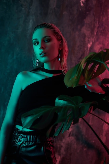 Fashion woman portrait in tropical foliage neon light. Wet hair, perfect figure and makeup