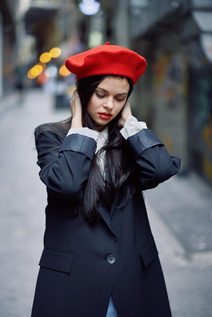 Foto moda donna ritratto turista a piedi in abiti eleganti con labbra rosse camminando per strada di città stretta viaggio colore cinematografico stile vintage retrò aspetto drammatico senza sorriso tristezza