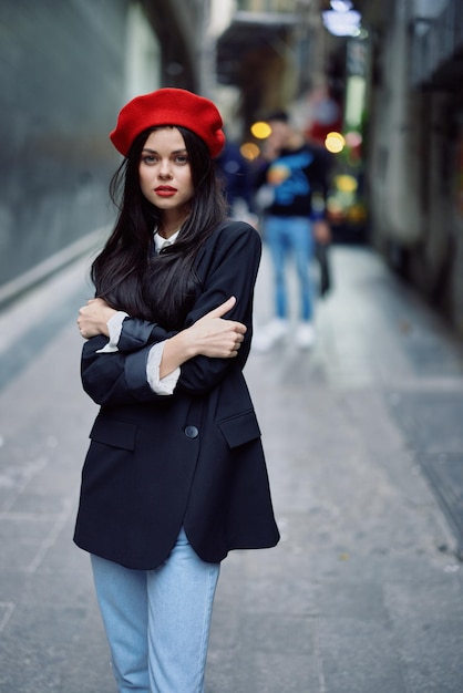 Fashion woman portrait walking tourist in stylish clothes with red lips walking down narrow city street travel cinematic color retro vintage style dramatic look without smile sadness