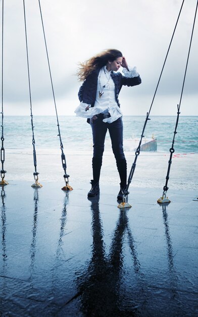 Fashion woman posing outdoor near ocean in windy day