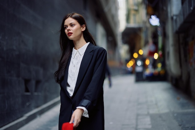 Модная женщина-туристка в стильной одежде в куртке и красном берете идет по узкой городской улице с развевающимися волосами и счастливым путешествием во французском стиле кинематографического цвета в стиле ретро