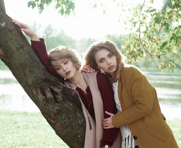 Fashion women posing together outdoor, autumn park.