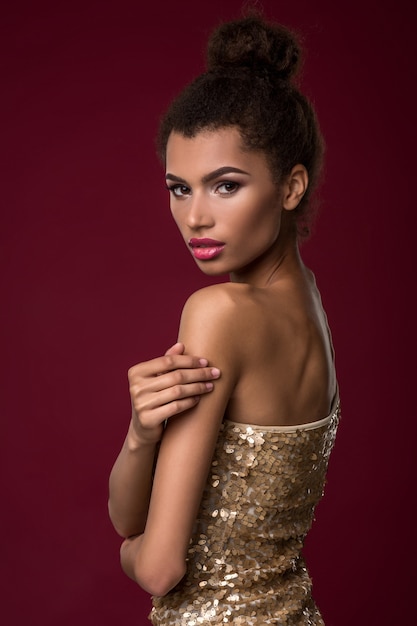 Fashion young african woman with makeup in sexy gold dress