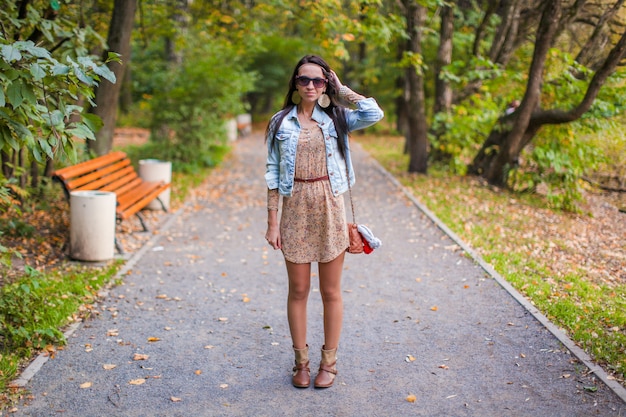 Fashion young beautiful girl walks in the park on a sunny autumn day