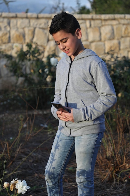 Fashion young boy wearing a hoody t shirt in park outdoors