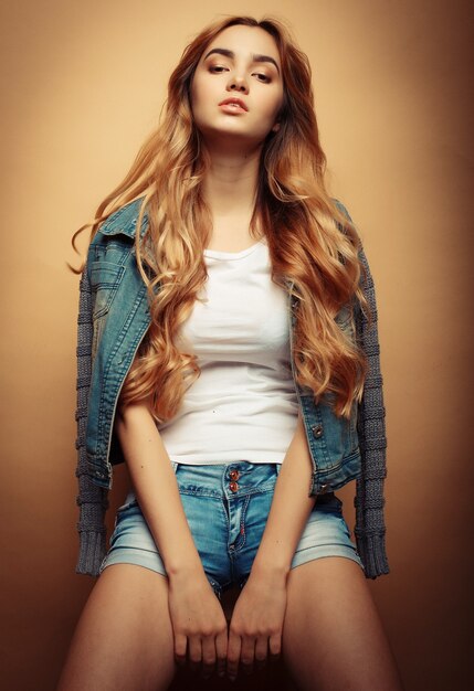 Fashion young model in nice clothes posing on yellow