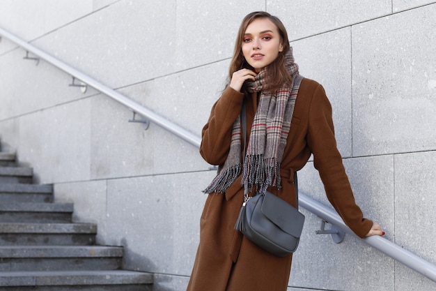 Fashion young woman outdoor wearing coat, scarf and handbag