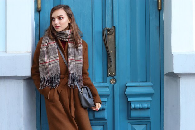 Fashion young woman outdoor wearing coat, scarf and handbag