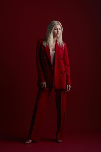 赤いスーツを着たファッションの若い女性。赤い背景。