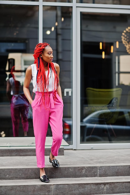 Ragazza afroamericana alla moda con pantaloni rosa e dreadlocks rossi poste all'aperto