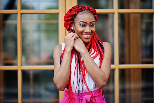 Fashionable african american girl at pink pants and red dreads posed outdoor