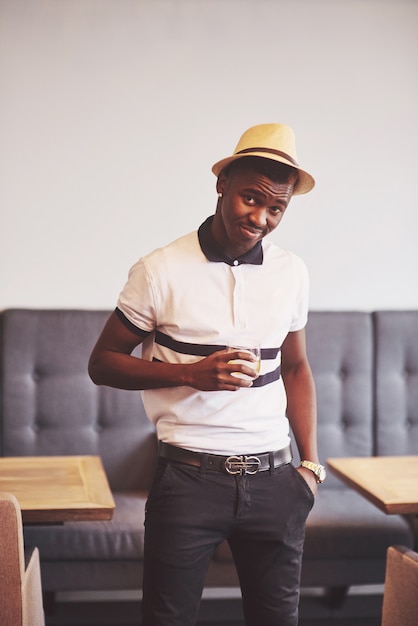 Fashionable african american man in hat with glass of whiskey