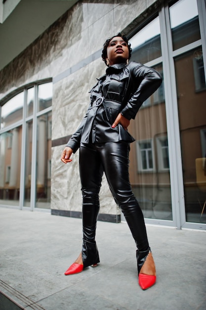 Fashionable beautiful african american woman posing in black leather jacket and pants at street