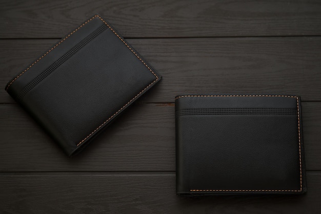 Fashionable black leather mens walletÃÂ on top of wooden table