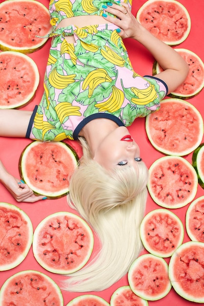 Fashionable blonde with makeup lying near watermelons