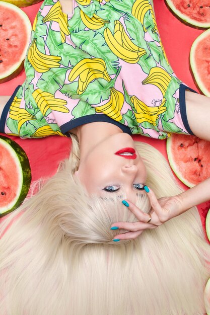 Fashionable blonde with makeup lying near watermelons