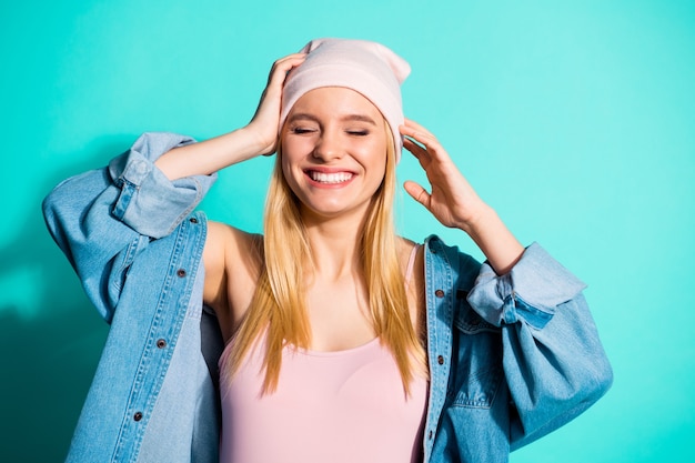 Foto donna bionda alla moda in posa contro il muro blu