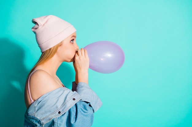 Fashionable blonde woman posing against the blue wall