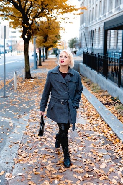 Foto donna bionda alla moda che cammina esplorando la città