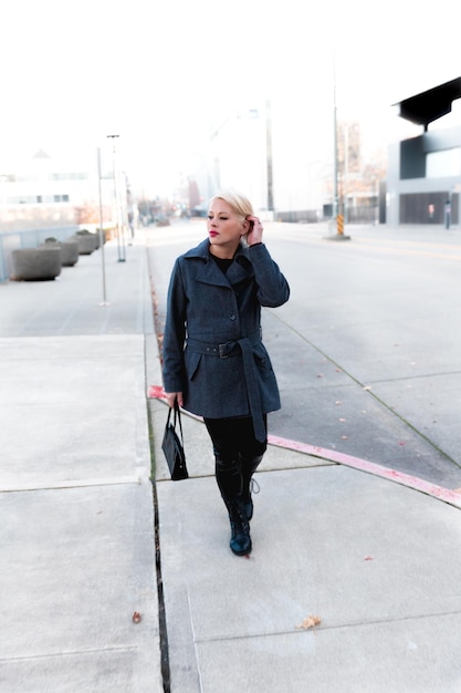 Foto donna bionda alla moda che cammina esplorando la città
