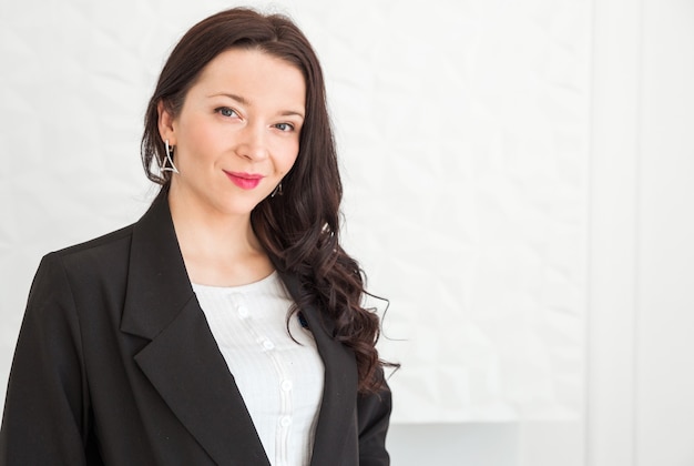 Fashionable brunette girl in a black jacket posing on a white background. Girl looking at the camera and smiling.  