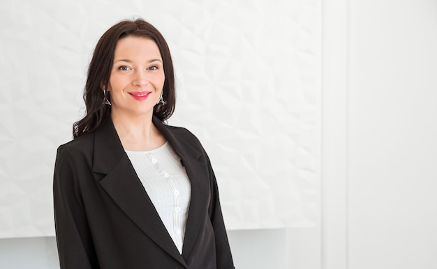 Fashionable brunette girl in a black jacket posing on a white background. Girl looking at the camera and smiling.  