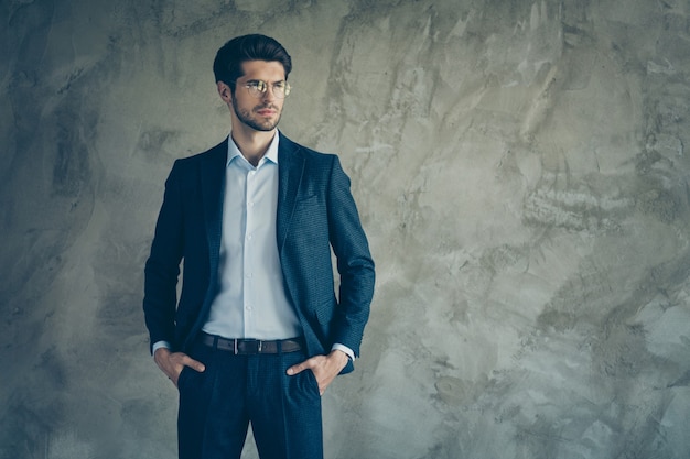 Fashionable businessman posing against the grey wall