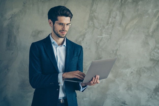 Fashionable businessman posing against the grey wall