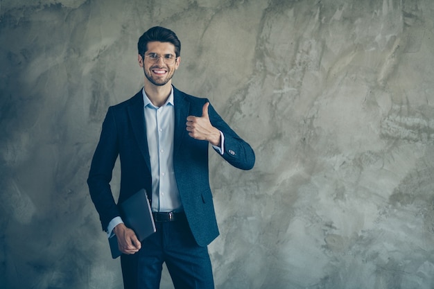 Fashionable businessman posing against the grey wall