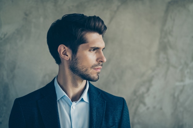 Fashionable businessman posing against the grey wall