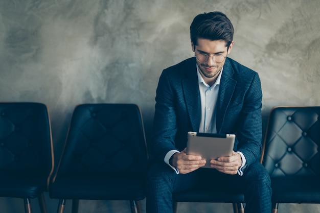 Fashionable businessman posing against the grey wall