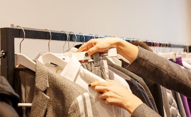 Fashionable clothes are hanging on hangers in store