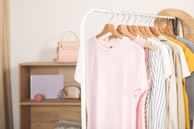 Fashionable clothes on hangers on a wardrobe rack in the background of the room