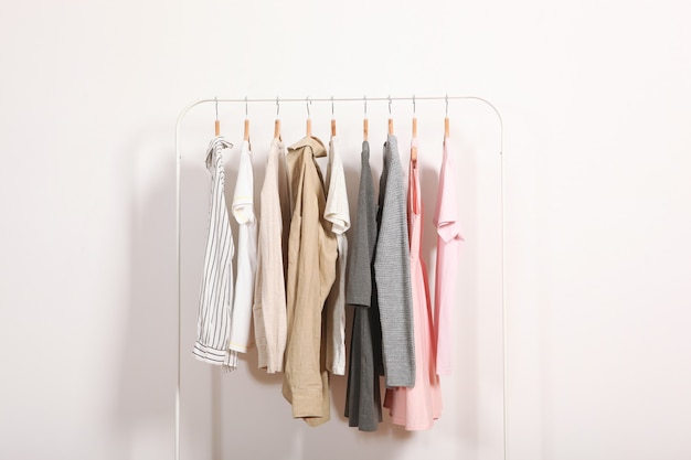 Fashionable clothes on hangers on a wardrobe rack on a colored background